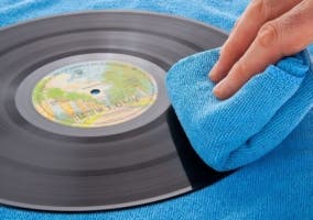 mano limpiando un disco de vinilo con un paño de microfibra