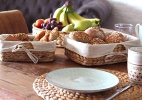 cestas con panes y fruta sobre mesa de madera