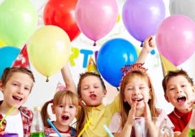 niños sonriendo en un cumpleaños con globos de colores detrás