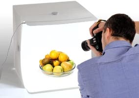 hombre fotografiando unas frutas ubicadas dentro de una cada de luz