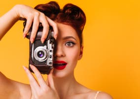 mujer con maquillaje vintage sosteniendo una cámara analógica